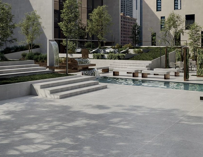 An open patio leads to a swimming pool in the Indiana gray style of landmark porcelain paver